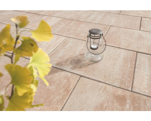 Gartenszene mit Terrassenplatten und Glaslaterne mit Kerze