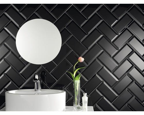 Salle de bain avec miroir rond, lavabo et mur de briques noires en motif à chevrons