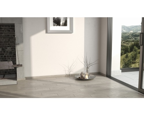 Heller Raum mit Steinboden, Kamin und Blick ins Grüne