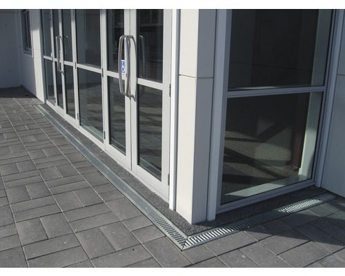 Douche plain-pied avec caniveau de drainage devant une porte