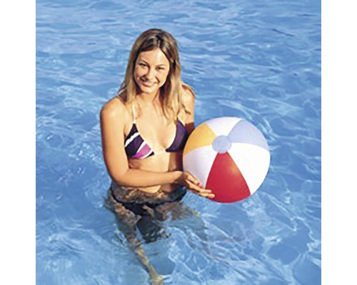 Femme dans la piscine tenant un ballon de plage