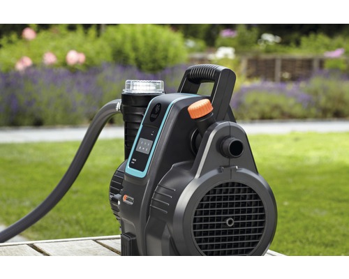 Gartenpumpe mit Schlauch auf einem Holztisch im Garten