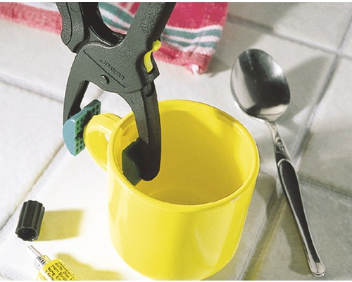 Tasse jaune fixée avec une pince à ressort pour faciliter un processus de collage.