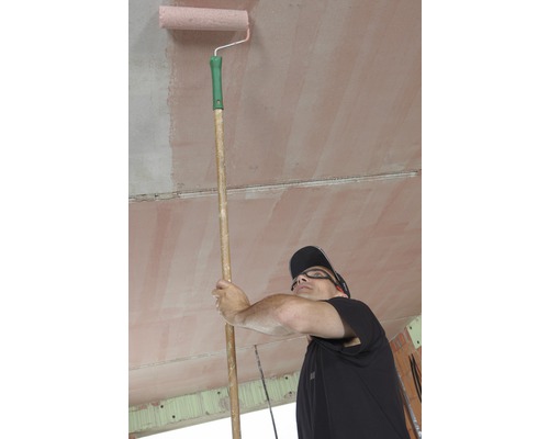 Homme peignant le plafond avec un rouleau de peinture sur un manche