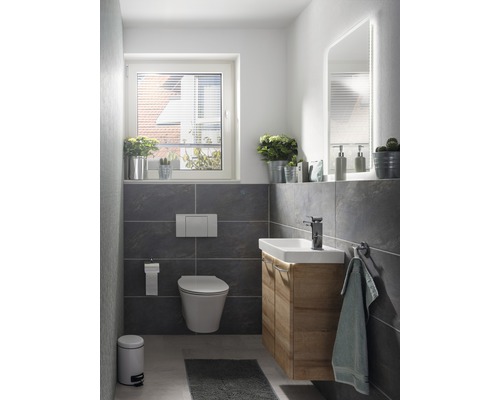 Badezimmer mit Toilette, Waschtisch, Spiegel und Fenster für ein helles Ambiente