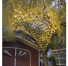 Guirlande lumineuse dans un arbre avec une lumière blanc chaud pour un éclairage de jardin d'ambiance
