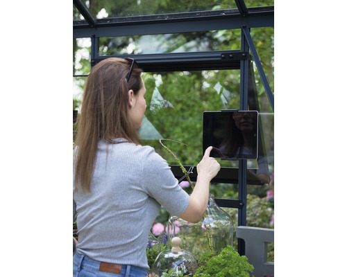 Femme utilisant une tablette dans une serre avec des plantes