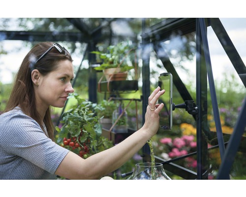 Femme utilisant une tablette dans une serre, entourée de plantes