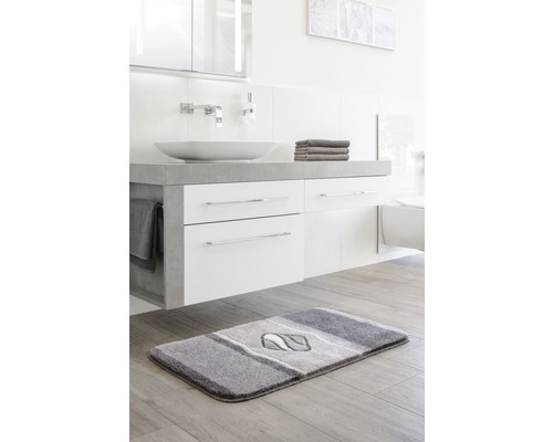 Salle de bain moderne avec tapis de bain gris devant un lavabo