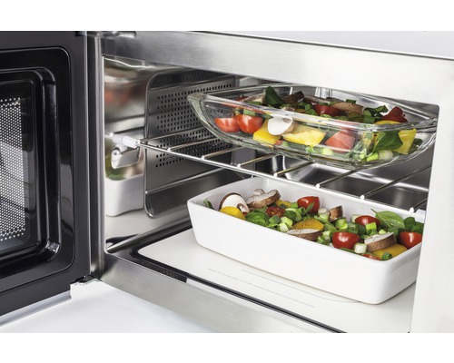 Four à micro-ondes ouvert en acier inoxydable avec des aliments dans un plat en verre et un plat en porcelaine