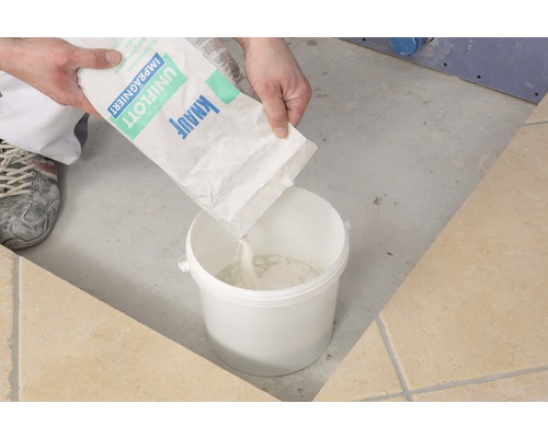 Personne versant du mastic de jointoiement Knauf Uniflott imprégné dans un seau