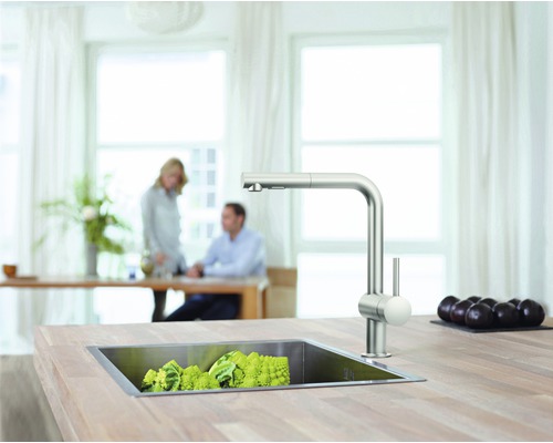 Scène de cuisine avec évier, robinet et légumes sur un plan de travail