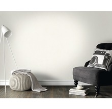 Salon avec lampe, fauteuil et coussin devant un mur