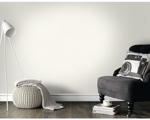 Salon avec lampe, fauteuil et coussin devant un mur