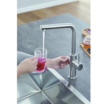 Küchenszene mit Spültischarmatur und Person, die einen Becher mit Tee befüllt