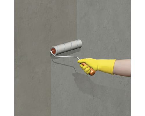 Une personne peint un mur gris avec un rouleau à peinture