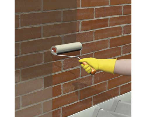 Une personne peint un mur en briques avec un rouleau à peinture.