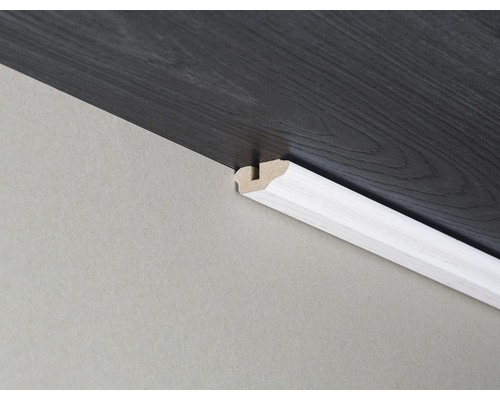 Weisse Viertelstab-Fussleiste zwischen Wand und dunklem Laminatboden