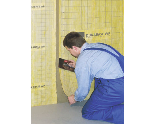 Un artisan applique le système d''étanchéité Durabase WP au mur à l''aide d''une spatule