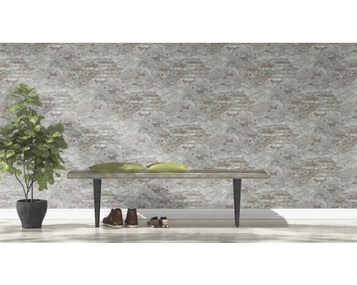 Dekoratives Interieur mit Bank, Kissen, Topfpflanze und Schuhen vor einer Wand mit Backsteinmuster