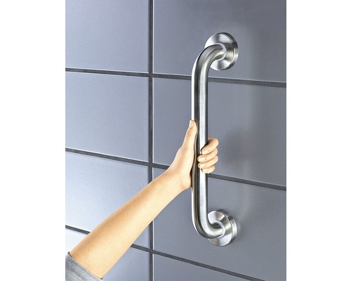 Une main tient une barre d''appui argentée dans une salle de bain.