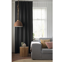 Salon avec canapé, table d''appoint en bois, lampe et rideau noir.