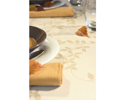 Décoration de table avec vaisselle et serviettes en tissu sur une nappe à motif de feuilles