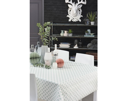 Dekorativer Esstisch mit Tischdecke, Vasen und Regal im Hintergrund.