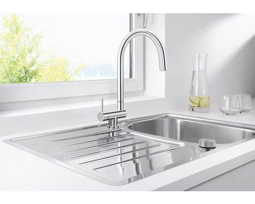 Évier de cuisine en acier inoxydable avec robinet devant une fenêtre