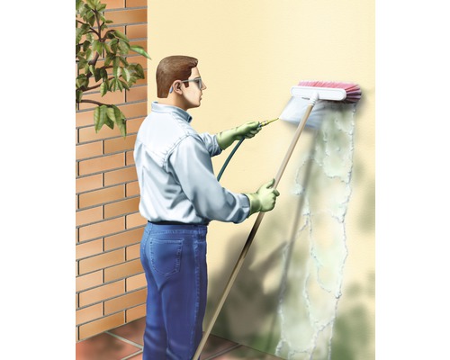 Mann reinigt eine Wand mit einer Bürste und einem Reinigungsmittel.