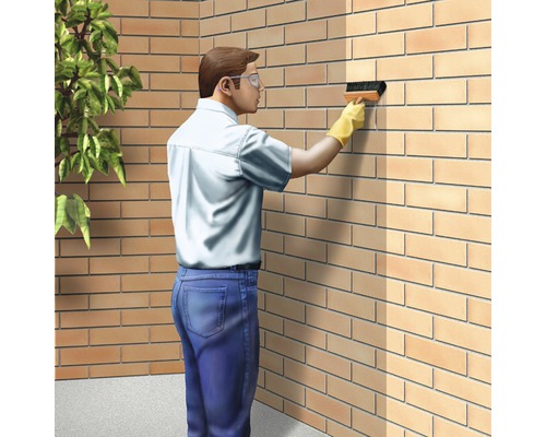 Mann mit Schutzbrille reinigt eine Backsteinmauer mit einer Bürste