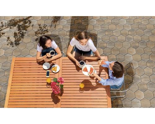 Trois femmes sont assises à une table en bois à l''extérieur et mangent des pizzas et des pâtisseries.