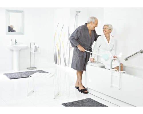 Salle de bain lumineuse avec baignoire, barres d''appui, élévateur de bain et deux personnes