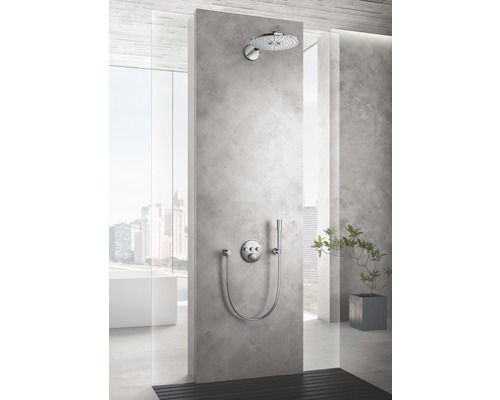 Douche avec pomme de tête et douchette à main sur un mur en béton gris dans une salle de bains.