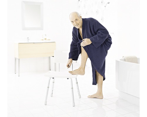 Un homme dans une salle de bains utilise un tabouret de douche.