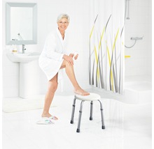 Salle de bains lumineuse avec une femme en peignoir assise sur un tabouret de douche
