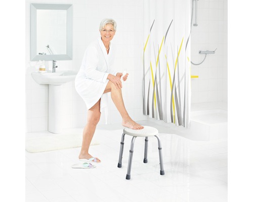 Salle de bains lumineuse avec une femme en peignoir assise sur un tabouret de douche