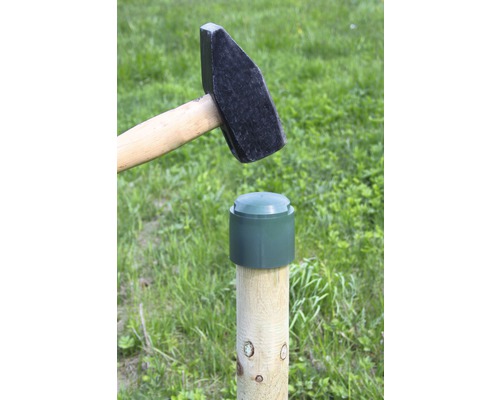 Hammer schlägt Kappe auf Holzpfosten