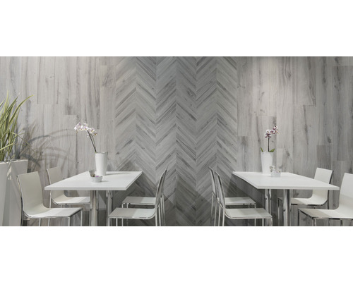 Pièce lumineuse avec carrelage mural aspect bois et motif à chevrons, tables et chaises