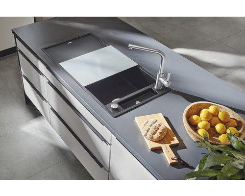 Évier avec planche à découper, robinetterie, pain sur planche à découper et bol de citrons sur un plan de travail