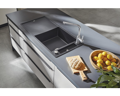 Évier avec robinet, planche à découper, pain et citrons sur comptoir de cuisine