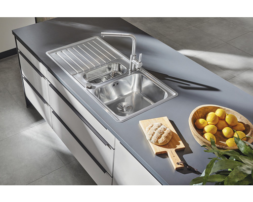 Évier de cuisine en acier inoxydable avec égouttoir et robinet sur un plan de travail