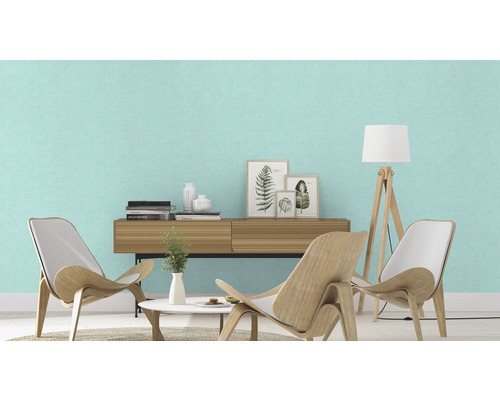 Salon lumineux avec papier peint textile vert menthe, meubles en bois et décorations pour une ambiance conviviale.