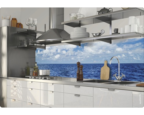 Cuisine claire avec hotte en acier inoxydable, armoires blanches et vue sur la mer