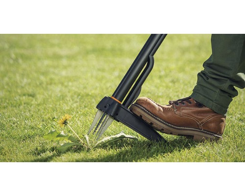 Une personne utilise un désherbeur dans le jardin pour enlever les pissenlits.