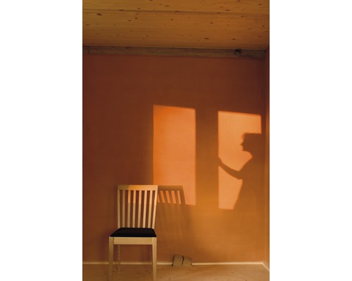 Intérieur avec plafond en bois, mur beige, chaise en bois avec coussin d''assise foncé et ombre d''une personne