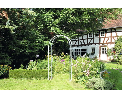 Gartenansicht mit Gartenbogen, Blumen und Fachwerkhaus im Hintergrund