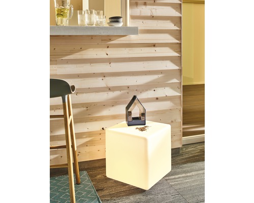 Scène avec un abreuvoir à oiseaux sur un cube lumineux à côté d''un bar et d''un tabouret de bar.