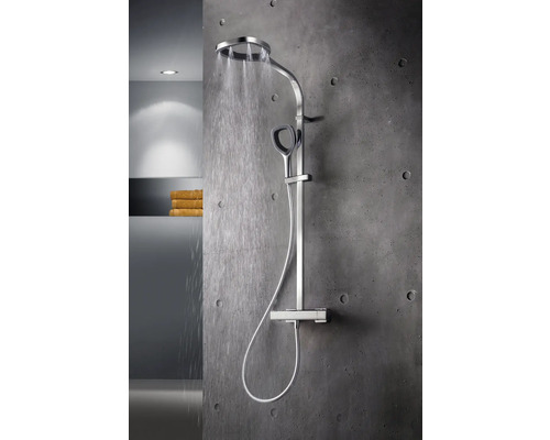 Système de douche apparent avec douche de tête et douchette à main sur un mur en béton