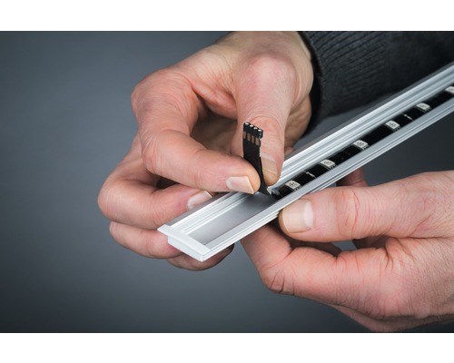 Eine Person installiert einen LED-Streifen in ein Aluminiumprofil.